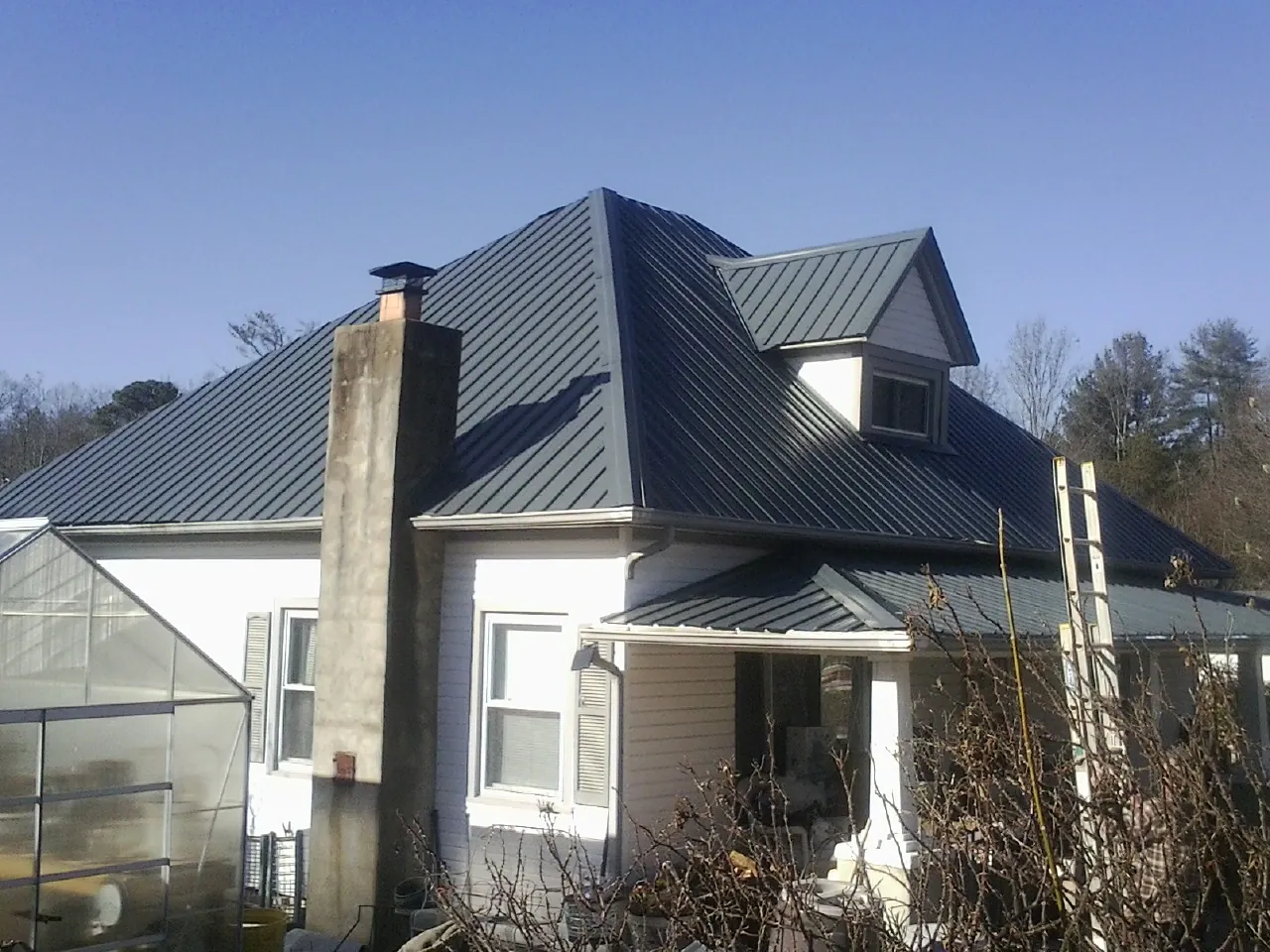 Dark blue standing seam metal roof on a white farmhouse with dormer — Slate & Tile Roof Repair by Roofing Brothers in Bon Aqua