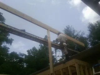 Carpenter setting a ridge beam over a new addition frame — Ice Dam Removal by Roofing Brothers in Bon Aqua
