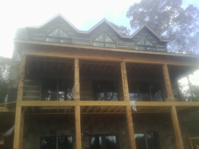 Dormers and porch framing on a large log home under construction — Roof Coating work by our crew in Bon Aqua