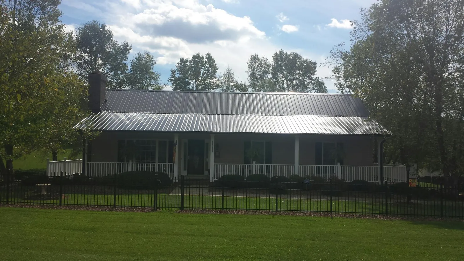 Gray metal roof on a brick ranch with a full width front porch — Gutter Guard Installation work by our crew in Bon Aqua