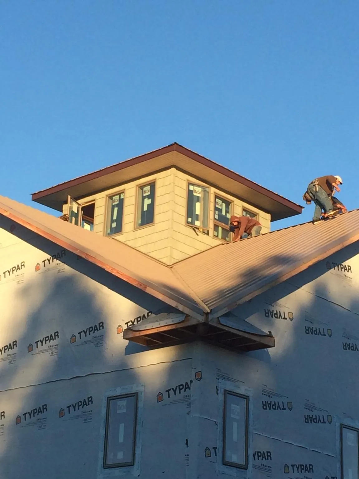 Roofers working around a rooftop cupola on a new metal roof at sunset — Roof Waterproofing in Bon Aqua by Roofing Brothers
